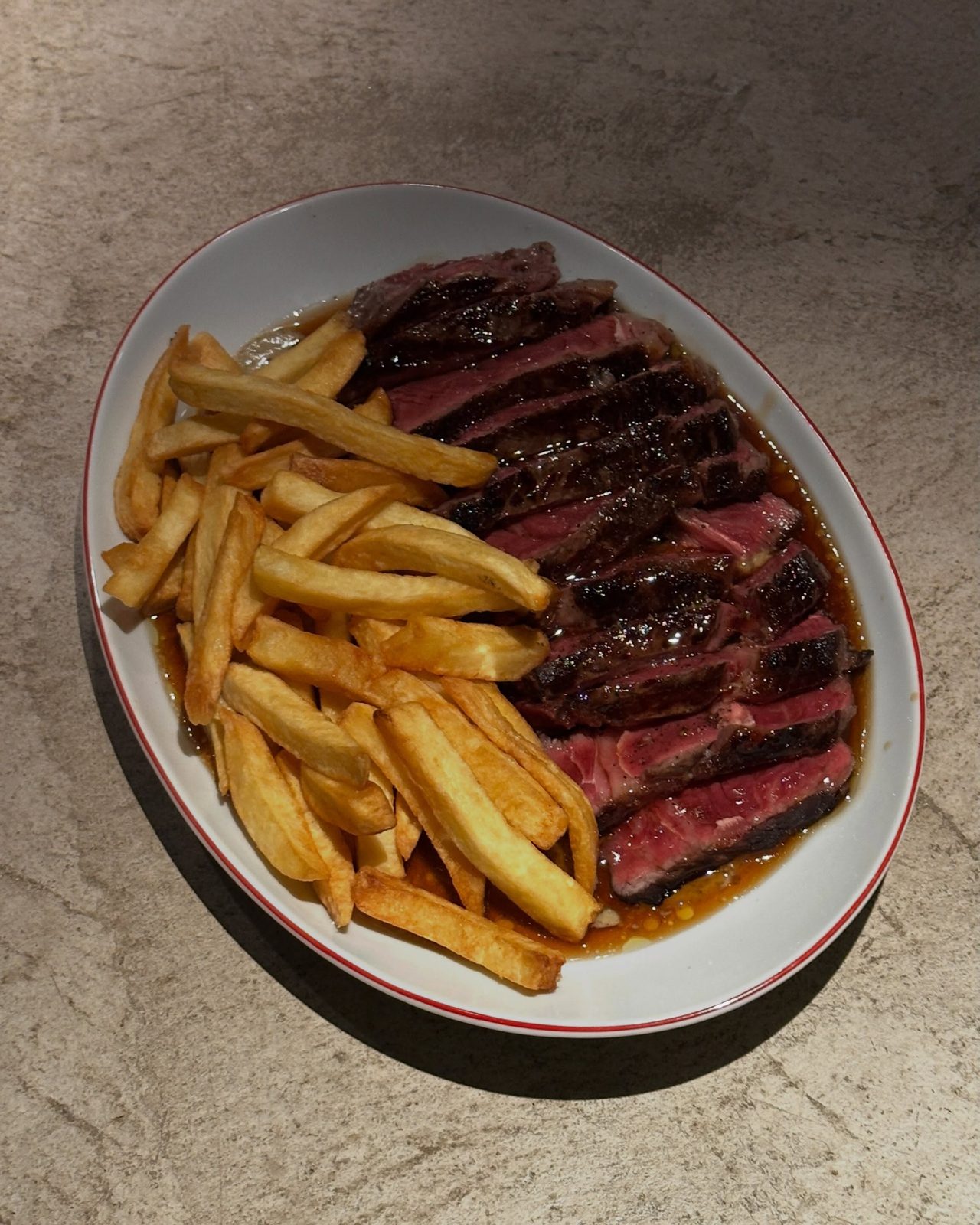 Steak frites: ojo de bife con papas fritas sobre plato de borde rojo